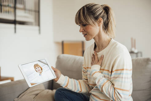Frau mit Hand auf der Brust bei einer Konsultation mit einem Arzt über einen Tablet-PC - JOSEF13599