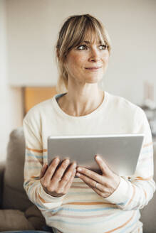 Thoughtful pregnant woman holding tablet PC at home - JOSEF13626