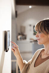 Woman touching tablet PC mounted on wall at home - JOSEF13671