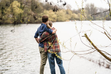 Couple embracing each other looking at lake - JOSEF13737