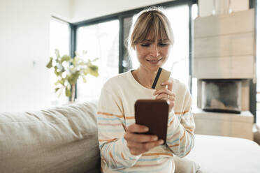 Lächelnde Frau beim Online-Einkauf mit Kreditkarte zu Hause - JOSEF13760