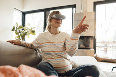 Schwangere Frau mit Virtual-Reality-Headset gestikuliert zu Hause - JOSEF13766