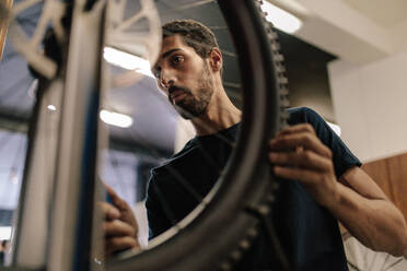 Ein Arbeiter richtet ein Fahrradrad in einer Werkstatt aus. Ein Mann arbeitet an einem Fahrrad in einer Reparaturwerkstatt. - JLPSF01694