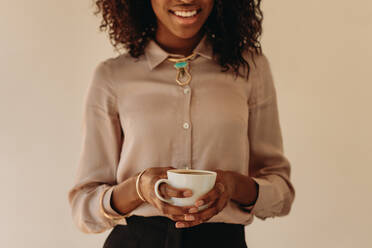 Close up of smiling businesswoman standing holding a coffee cup in hands. - JLPSF01768