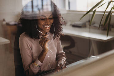 Businesswoman working on laptop computer and talking using earphones sitting at home. Businesswoman managing business from home working on laptop. - JLPSF01777