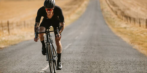 Profi-Sportler Radfahren auf langen Landschaft Autobahn. Sportler Radfahren bergauf auf der ländlichen Asphaltstraße. - JLPSF01828