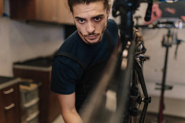 Closeup of a man working on a bicycle in a repair shop. Worker fixing a bicycle in workshop. - JLPSF01846