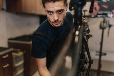 Nahaufnahme eines Mannes, der in einer Werkstatt an einem Fahrrad arbeitet. Arbeiter, der ein Fahrrad in einer Werkstatt repariert. - JLPSF01846