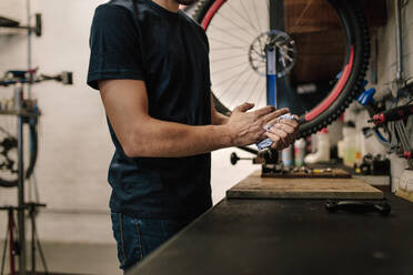 Worker cleaning his hands after repairing bicycle in workshop. Cropped shot of mechanic working in a bicycle repair shop. - JLPSF01853