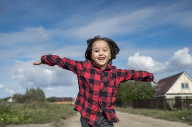 Happy boy running with arms outstretched on sunny day - ANAF00057