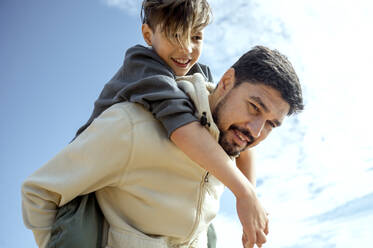Vater nimmt seinen Sohn an einem sonnigen Tag huckepack - ANAF00066