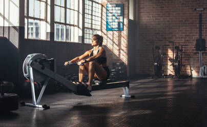 Frau beim Muskeltraining im Fitnessstudio. Sportler beim Training im Fitnessstudio durch Ziehen von Gewichten. - JLPSF01963