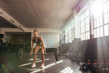 Frau, die im Fitnessstudio schwere Gewichte hebt, um ihre Muskeln zu trainieren; Sportler, der mit einer Hantelstange trainiert. - JLPSF01964