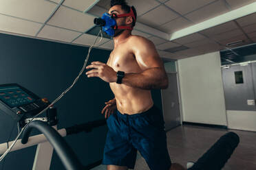 Athlete doing a performance test in sports lab. Runner with mask running on treadmill machine and testing performance. - JLPSF01968