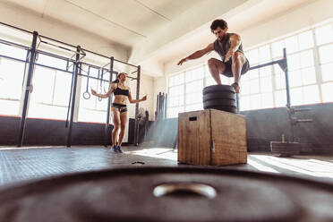 Fit junger Mann Box-Springen mit Frau übt mit Springseilen in einem Cross-Training-Stil Fitness-Studio. Paar während intensiver Workout-Sitzung im Fitness-Club. - JLPSF02022