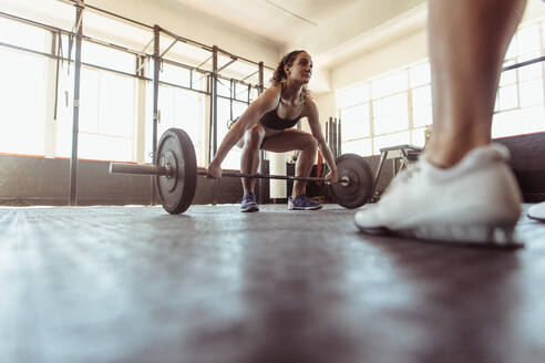 Muskulöse Frau, die in einem Fitnessstudio Gewichte hebt. Fitte Sportlerin, die im Fitnessstudio trainiert. - JLPSF02035
