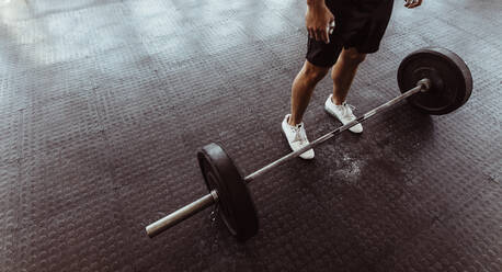 Ein Mann trainiert mit einer Langhantel in einem Fitnessstudio. Ein Mann steht mit schweren Gewichten auf dem Boden des Fitnessstudios. - JLPSF02038
