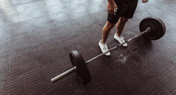 Ein Mann trainiert mit einer Langhantel in einem Fitnessstudio. Ein Mann steht mit schweren Gewichten auf dem Boden des Fitnessstudios. - JLPSF02038