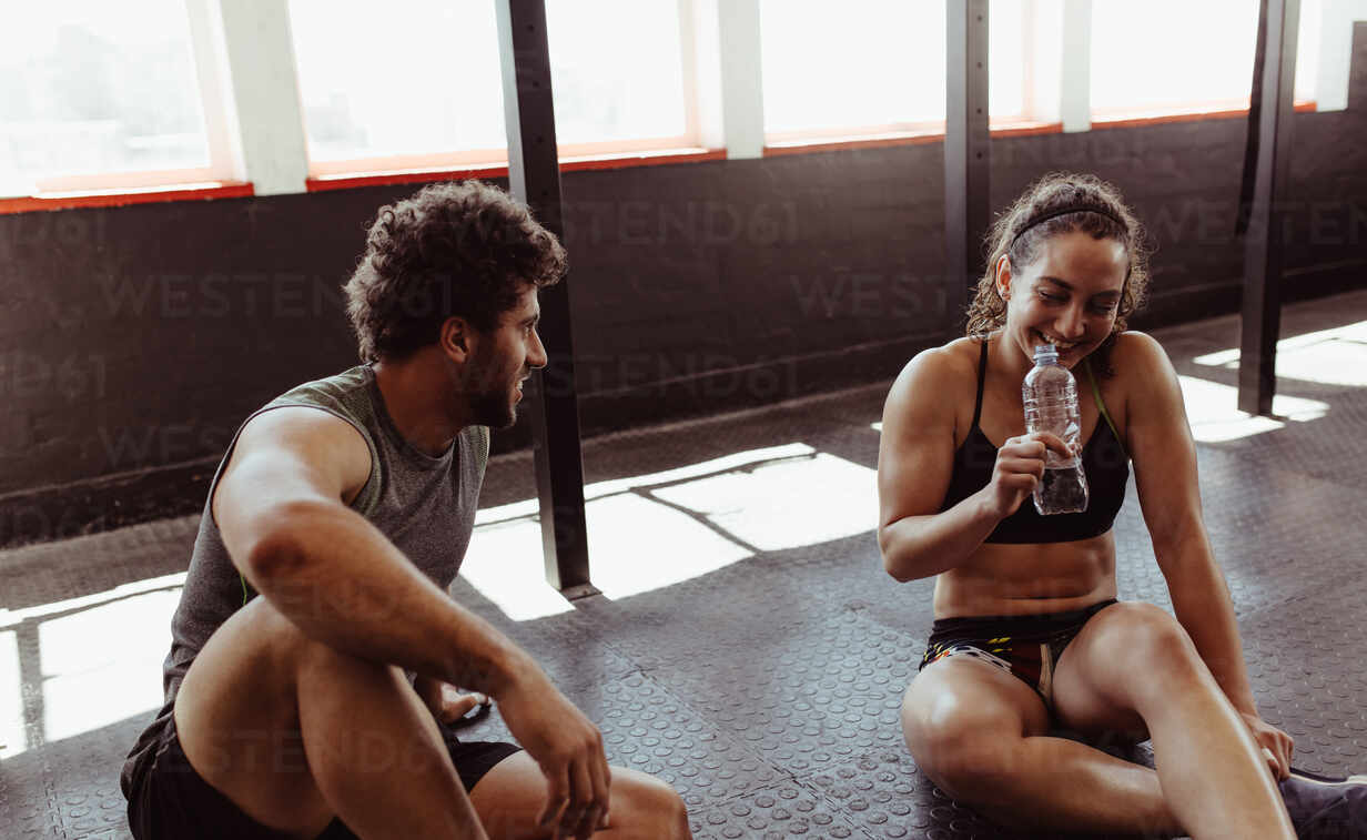 https://us.images.westend61.de/0001721426pw/young-people-sitting-on-floor-and-relaxing-in-gym-after-training-with-woman-drinking-water-couple-relaxing-after-workout-session-at-gym-JLPSF02059.jpg