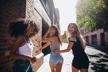 Mixed raced group of friends walking together in city. Three young people having fun outdoors on road. - JLPSF02067