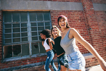 Three young adults walking together having fun. Stylish young women walking outdoors in city and smiling. - JLPSF02069