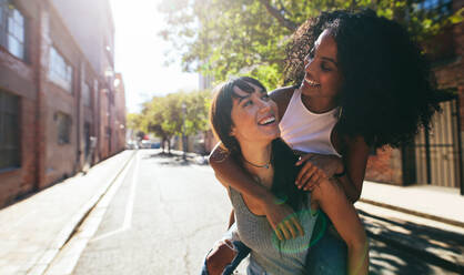 Two happy young women friends hugging in the street. - a Royalty