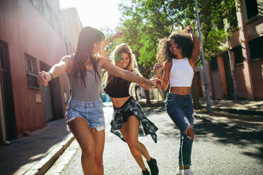 Außenaufnahme von jungen Frauen, die sich auf der Straße amüsieren, Freundinnen, die einen Tag in der Stadt genießen. - JLPSF02079