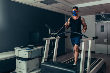 Male runner with mask running on treadmill machine testing his performance. Athlete examining his fitness in biomechanics lab. - JLPSF02082