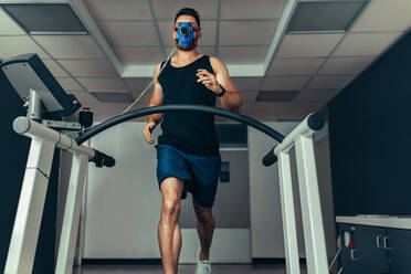 Athlete examining his fitness in sports lab. Runner with mask running on treadmill machine and testing performance. - JLPSF02087