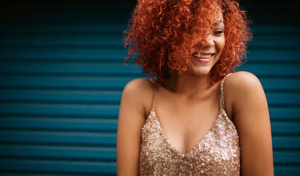 Close up of a smiling young woman in a glamorous dress. Young woman in golden brown curly hair smiling. - JLPSF02136