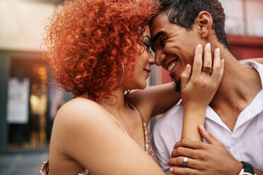 Nahaufnahme eines jungen Paares in romantischer Stimmung, das sich lächelnd anschaut. Die Frau hält ihren Partner sinnlich fest, ihre Hand liegt auf seinem Gesicht und ihre Köpfe berühren sich. - JLPSF02137