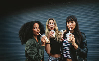 Schöne junge Frauen beim Eiskaffee im Freien. Multirassische Gruppe von Freundinnen beim Kaffeetrinken. - JLPSF02147