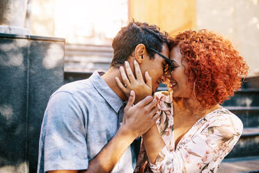 Nahaufnahme eines jungen romantischen Paares, das eng beieinander sitzt und sich an der Stirn berührt. Ein glücklicher junger Mann und eine Frau in romantischer Stimmung drücken ihre Liebe aus. - JLPSF02152