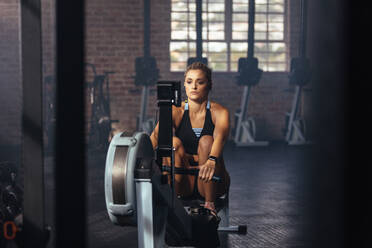 Junge Frau beim intensiven Training im Fitnessstudio. Frau beim Muskeltraining durch Ziehen von Gewichten im Fitnessstudio. - JLPSF02168