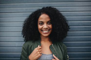 Close up portrait of smiling african woman standing against gray background. Afro american woman looking at camera. - JLPSF02192