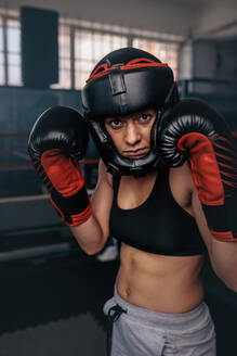 Nahaufnahme einer weiblichen Boxerin in ihrer Boxausrüstung. Eine Boxerin in einem Boxstudio trägt einen Kopfschutz und Boxhandschuhe. - JLPSF02217