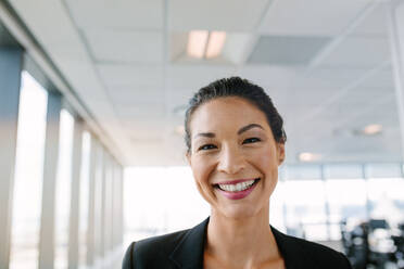 Porträt einer schönen reifen Geschäftsfrau, die im Büro steht und lächelt. Asiatische Unternehmerin schaut mit einem breiten Lächeln in die Kamera. - JLPSF02255
