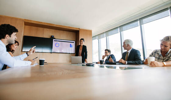 Geschäftskollegen, die in einem Konferenzraum zusammenarbeiten. Eine multiethnische Gruppe von Geschäftsleuten bespricht eine Geschäftsstrategie. - JLPSF02264