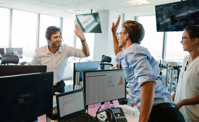 Erfolgreiche Geschäftsleute sehen glücklich aus und geben sich ein High Five. Kollegen feiern ihren Erfolg im Büro. - JLPSF02302