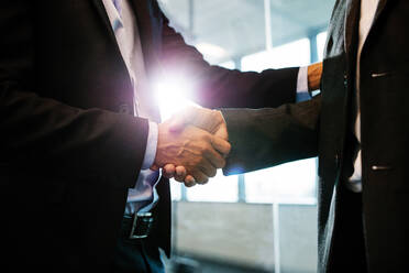 Close up of business people shaking hands in office. Business men shaking hands with each other. - JLPSF02364