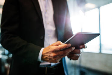 Cropped image of male entrepreneur with digital tablet in office. Focus on hands of businessman with touchpad. - JLPSF02365