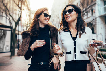 Two females walking together on the city street. Women friends walking on the road. - JLPSF02382