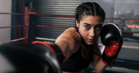 Nahaufnahme einer weiblichen Boxerin beim Schattenboxen in einem Boxring. Eine Boxerin übt ihre Schläge in einem Boxstudio. - JLPSF02393