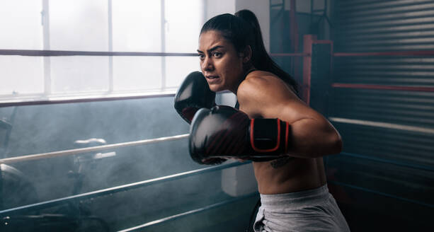 Weibliche Boxerin beim Schattenboxen in einem Boxring. Eine Boxerin übt ihre Schläge in einem Boxstudio. - JLPSF02406