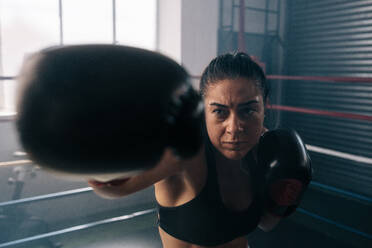 Eine Boxerin übt ihre Schläge in einem Boxstudio. Nahaufnahme einer weiblichen Boxerin, die in einem Boxring schlägt. - JLPSF02411