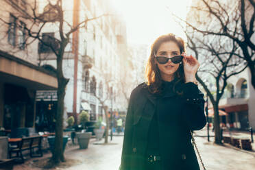 Attraktive junge Frau mit Sonnenbrille auf der Straße. Kaukasische Frau in der Stadt mit Blick auf eine Aussicht. - JLPSF02427