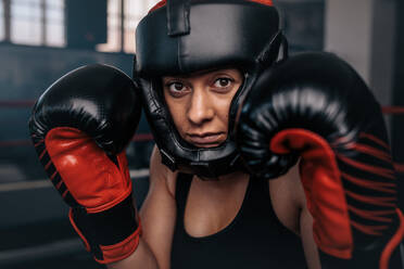 Close up of a female boxer in her boxing gear. Woman boxer at a boxing studio wearing head guard and boxing gloves. - JLPSF02436