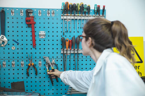 Techniker nimmt Arbeitswerkzeug aus dem Regal in der Werkstatt - PCLF00025