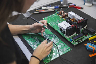 Woman soldering motherboard on table in workshop - PCLF00026