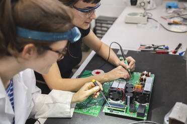 Female technicians soldering motherboard on table in workshop - PCLF00029